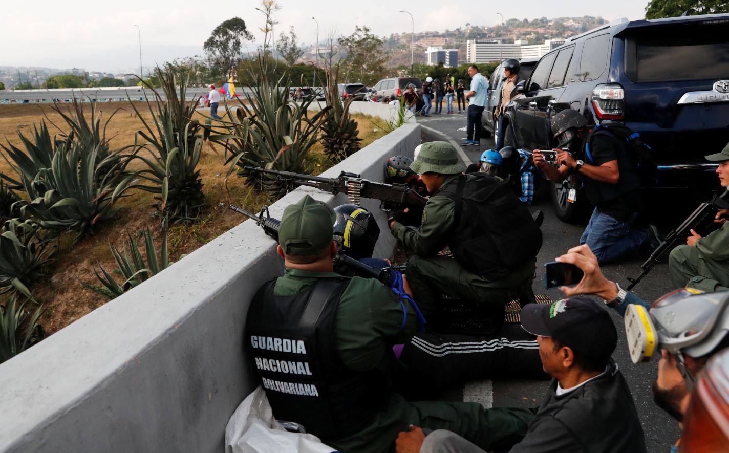 Soldados que apoyan el levantamiento militar de Juan Guaido toman cubierta ante el sonido de múltiples disparos provenientes de la base 'La Carlota' (Reuters)