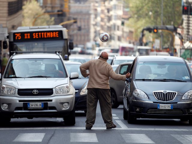Un hombre pide dinero después de concluir una rutina de entrenamiento de futbol en las calles de Roma (Reuters)
