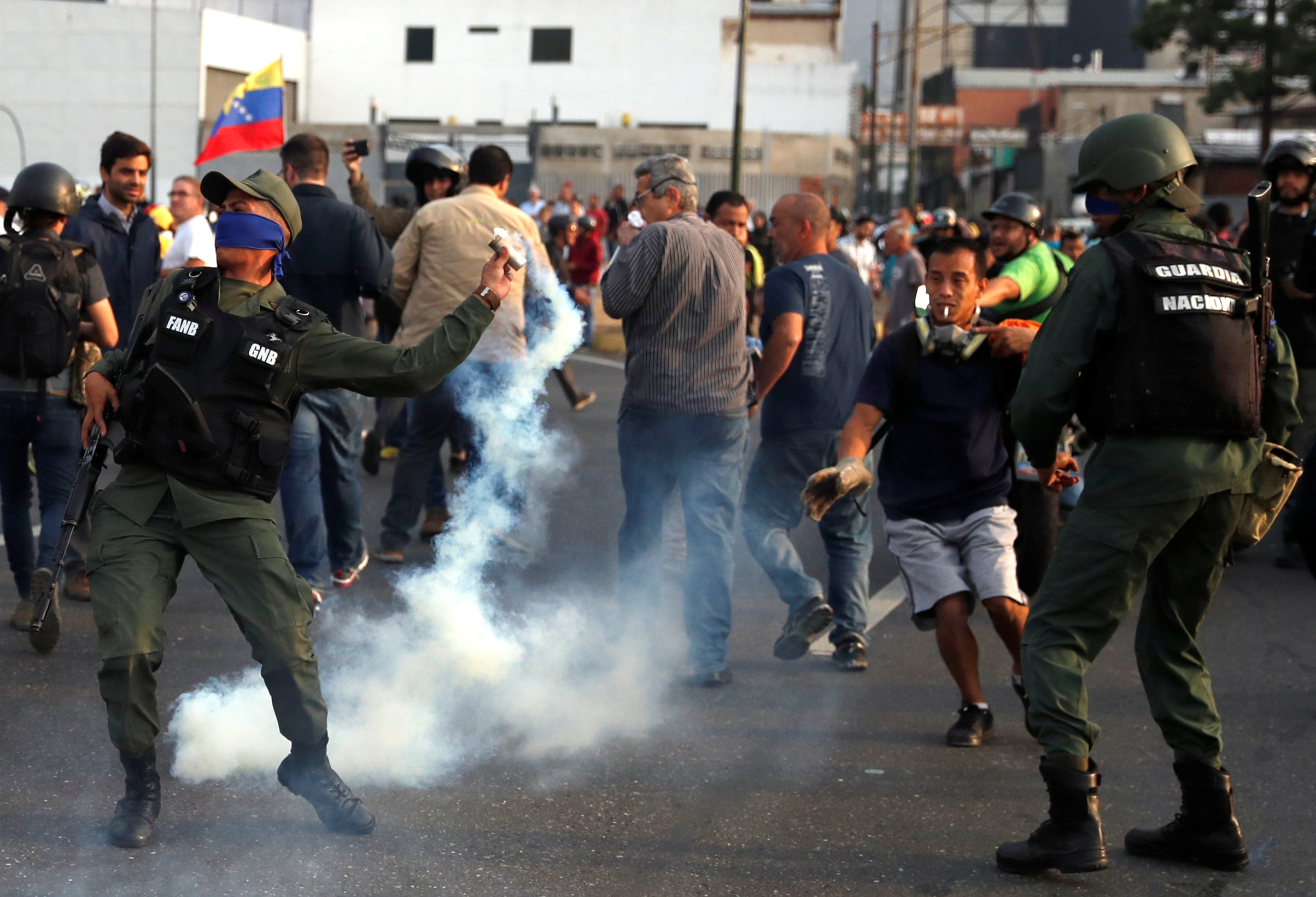 Un militar arroja de vuelta un cartucho de gas lacrimógeno disparado hacia la concentración de opositores políticos (Reuters)