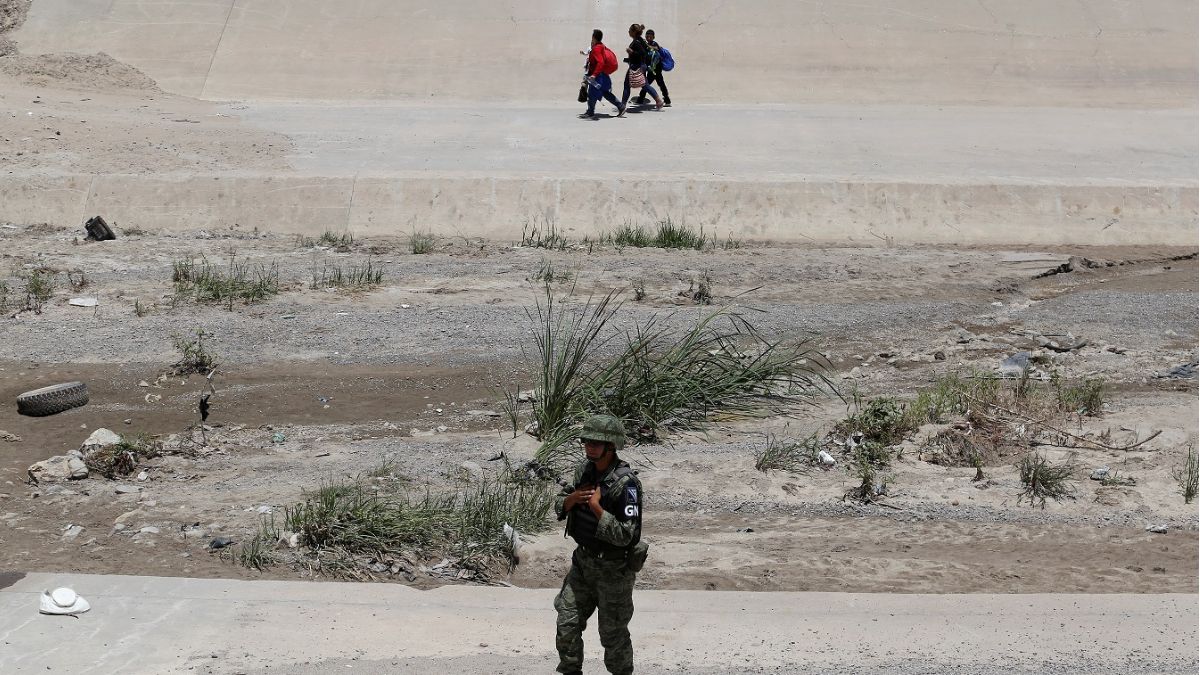 Foto: Un miembro de la Guardia Nacional de México vigila mientras una familia migrante camina por la orilla del Río Bravo después de cruzar ilegalmente hacia Estados Unidos. El 25 de junio de 2019
