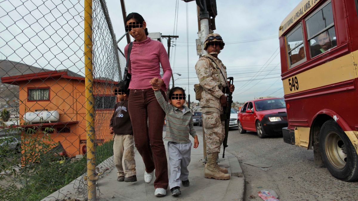 Foto: Una mujer con hijos camina junto a un soldado cerca de un puesto de control militar en Tijuana, México. El 16 de enero de 2010