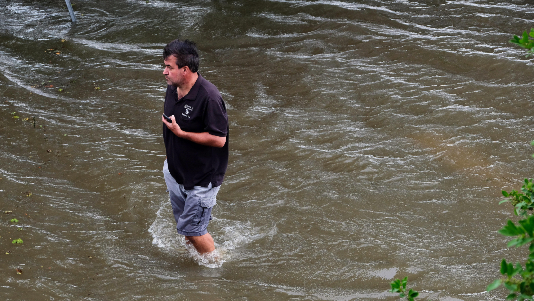 fOTO: Un sujeto camina a través de un área inundada cerca del lago Pontchartrain en Mandeville, Louisiana, 13 julio 2019