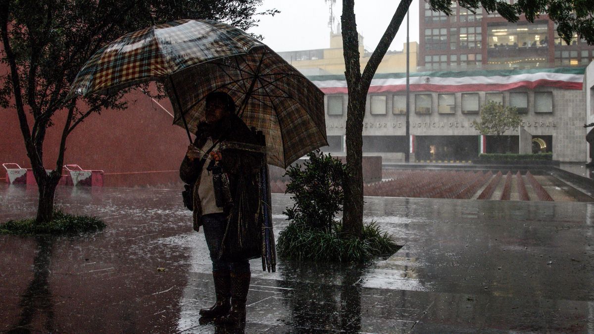 Foto: Una persona se cubre de la lluvia con dos paraguas en la zona centro de la Ciudad de México. Cuartoscuro