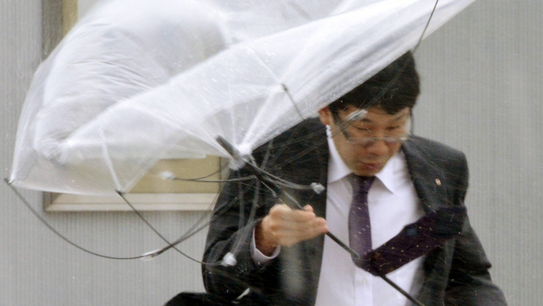 Foto: Un hombre se protege de la lluvia y los fuertes vientos provocados por un tifón, 8 septiembre 2019