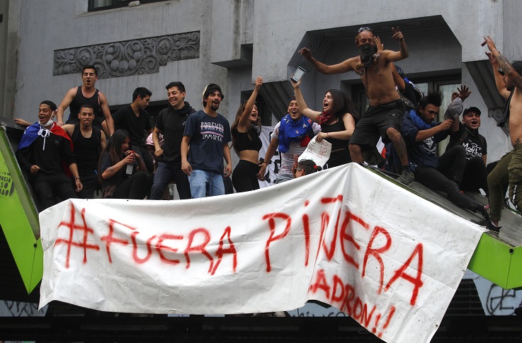 Foto: Manifestantes cargan una manta con la leyenda “Fuera Piñera”. Getty Images