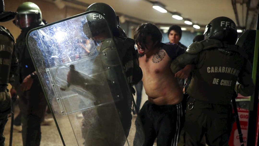 Carabineros de la Policía chilena retienen a un manifestante en la estación del metro en Santiago, Chile, 19 octubre 2019