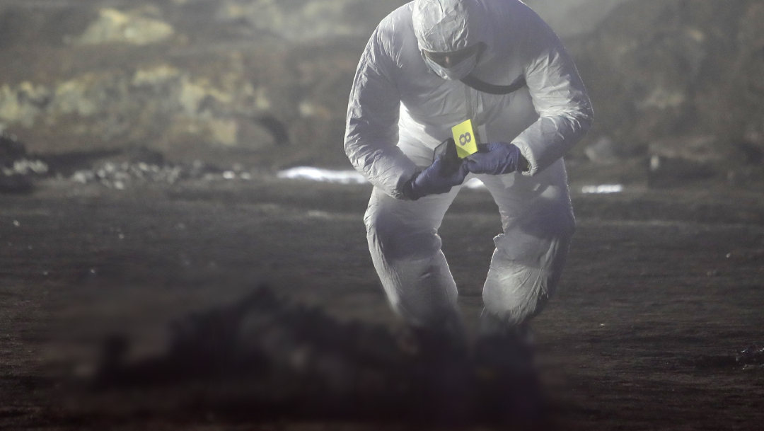 FOTO: Un médico forense trabaja con cuerpos quemados tras la explosión en un ducto de Pemex por una toma clandestina, 19 enero 2'019