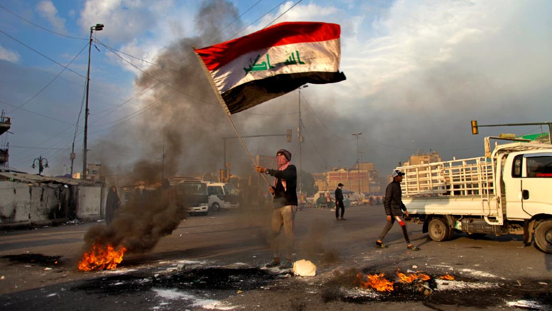 Foto: Un hombre ondea la bandera de Irak durante protestas contra ataque de misiles iraníes en Bagdad, el 10 de enero de 2020 (AP)