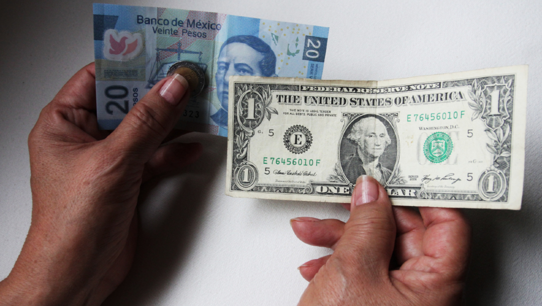 Foto: Una persona sostiene en su mano izquierda un billete de veinte pesos mexicanos y en la derecha un dólar, 8 enero 2020
