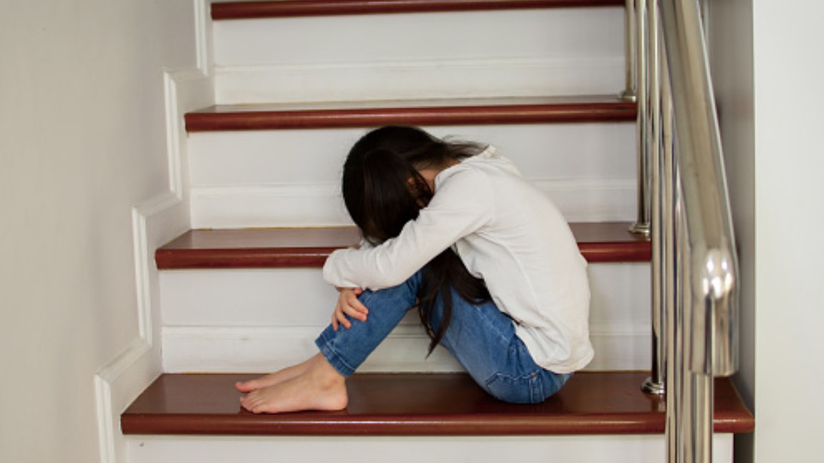 Foto: Una niña sentada en las escaleras se cubre el rostro. Getty Images/Archivo