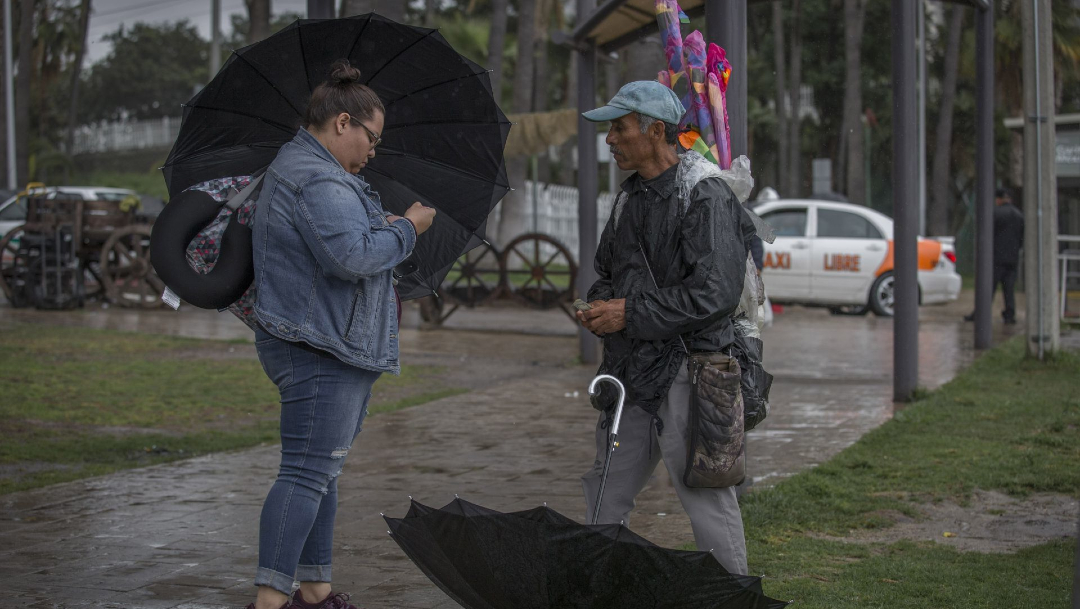 Dos personas se cubren de la lluvia que se registra en algunos estados del país. (Foto: cuartoscuro)