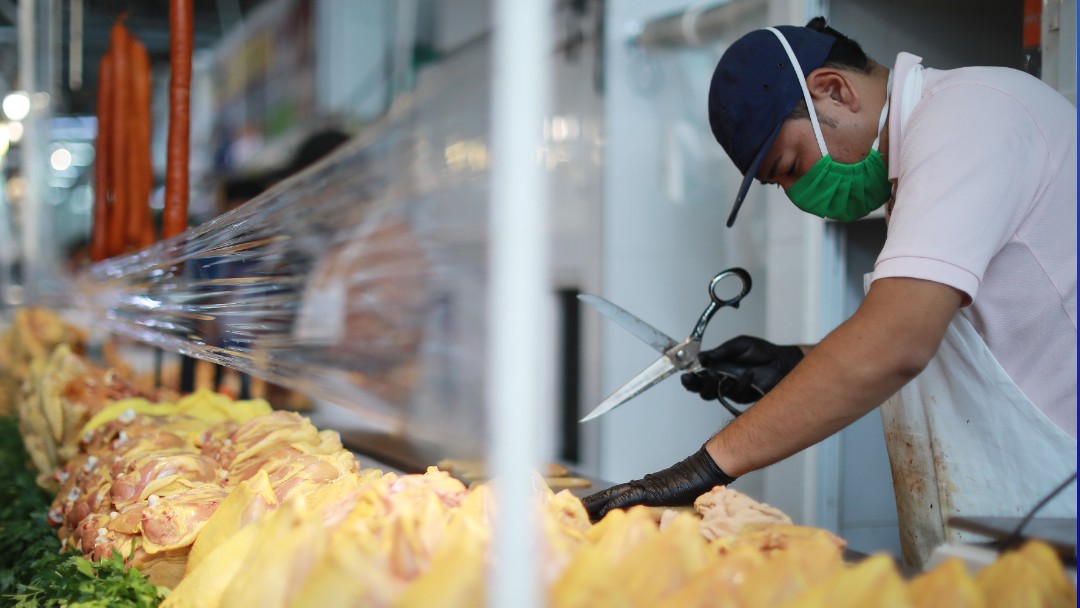 Un joven usa cubreboca mientras corta pollo en un mercado de la CDMX. Getty Images