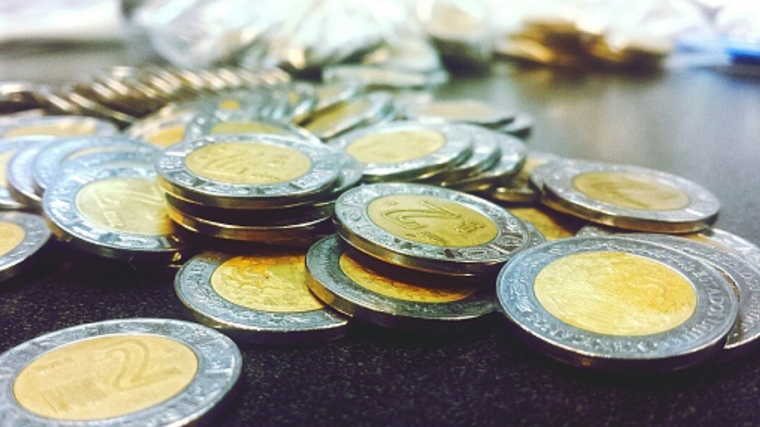 Tiran en una mesa monedas de dos pesos y un peso mexicano. Getty Images