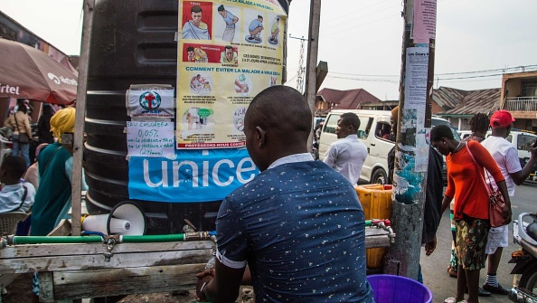 Hombre frente a letrero de medidas contra ébola en Congo, África