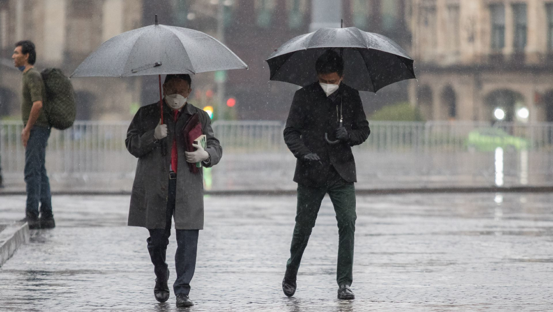 Dos personas se protegen de la lluvia bajo un paraguas en la Ciudad de México.