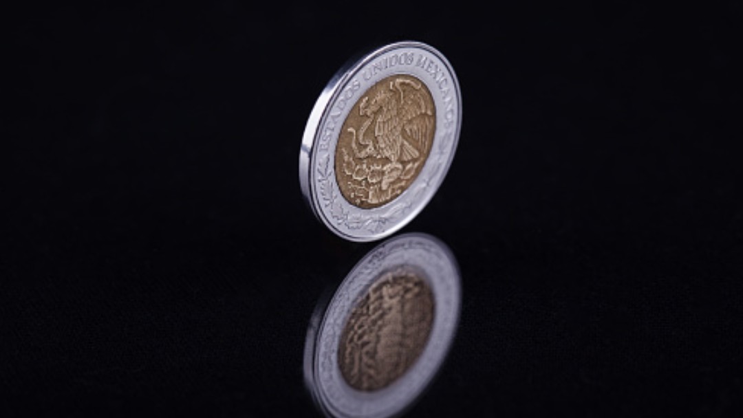 Moneda de un peso mexicano rueda en una mesa. Getty Images