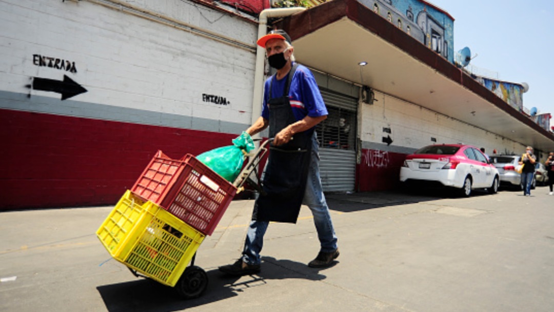 Un señor empuja un "diablo" con cajas con comida en un mercado de CDMX. Getty Images