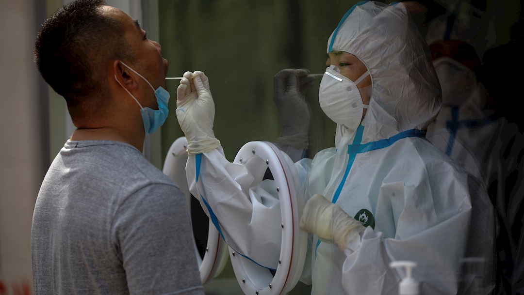 Un trabajador médico con un equipo de protección completo examina a un hombre. (Foto: EFE)