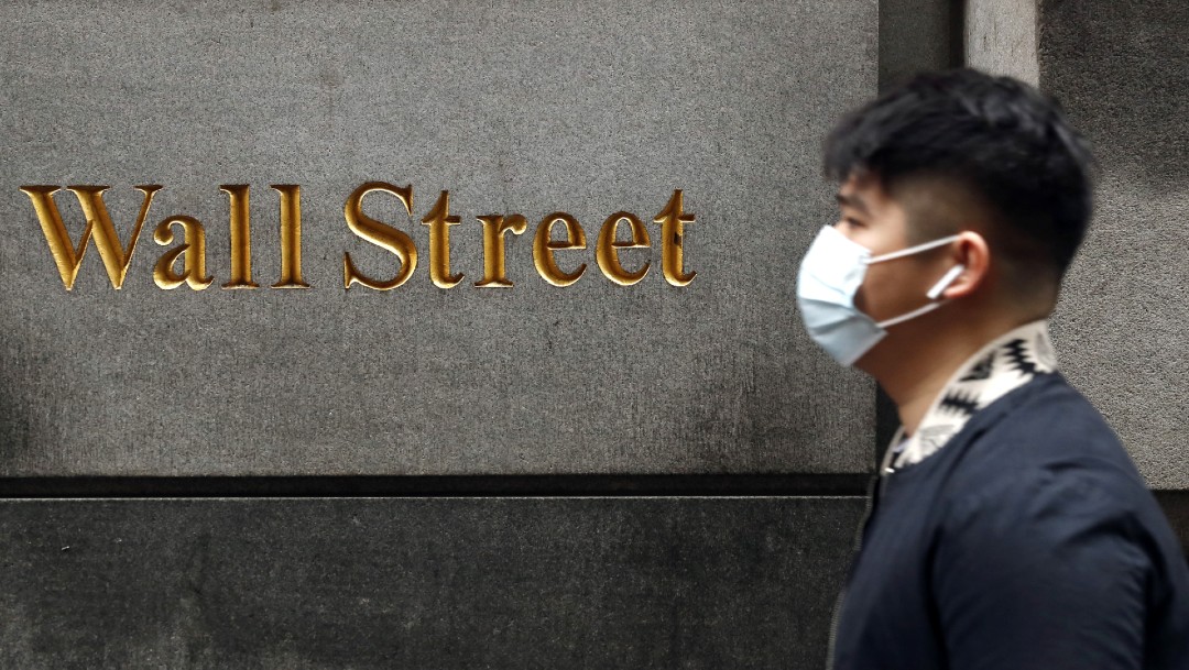 Hombre con cubrebocas camina frente a Wall Street en Nueva York