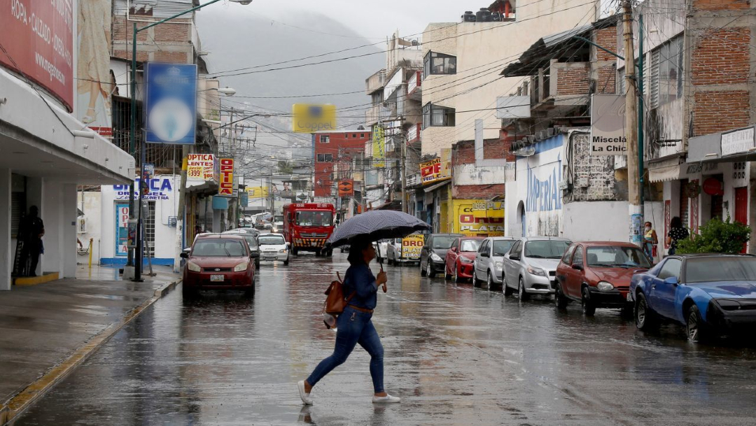 Una mujer se protege de la lluvia que se registra en varios estados del país.