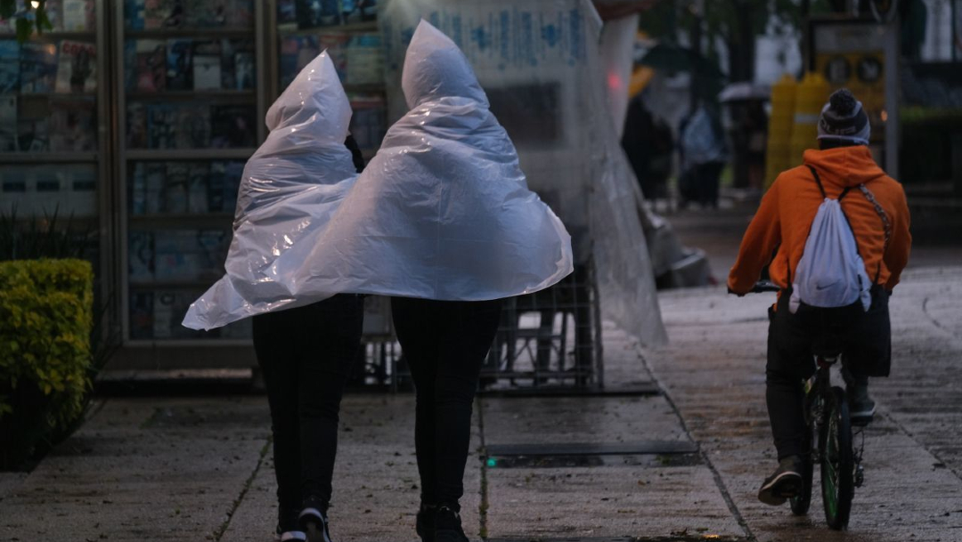 Transeúntes utilizan paraguas y rompe vientos para cubrirse de la lluvia