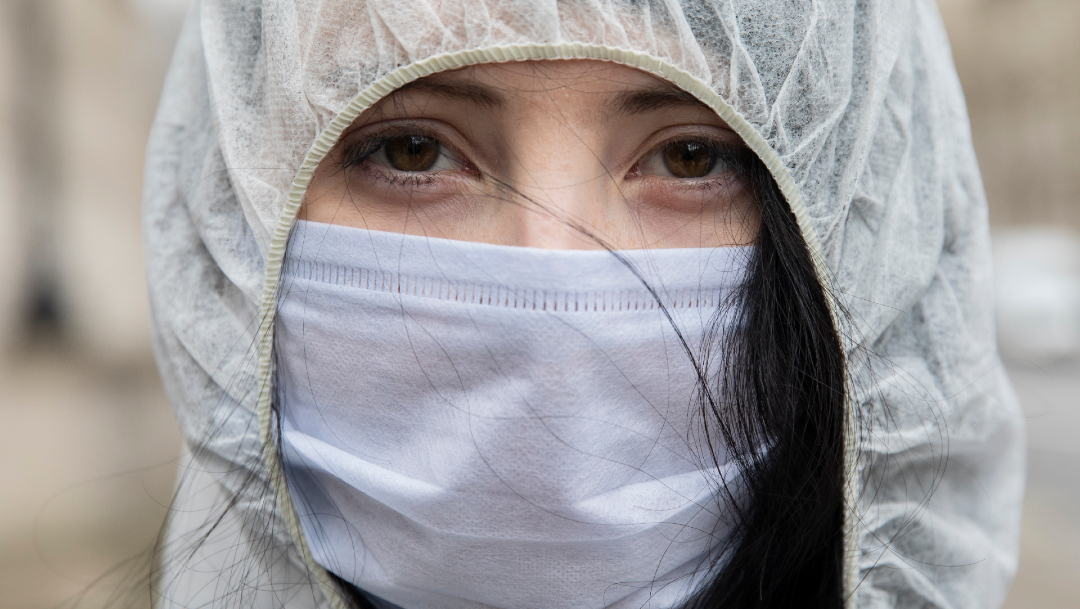Mujer usando cubrebocas, muertos por COVID en todo el mundo superan la barrera de los 560,000