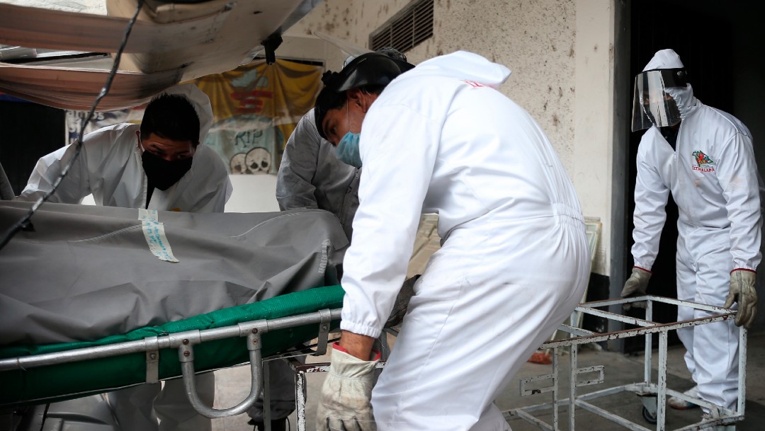 Trabajadores de un velatorio trasladan el cuerpo de un fallecido por coronavirus en CDMX