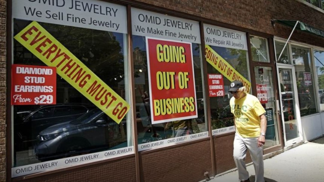 Un hombre camina frente a joyería cerrada en Estados Unidos; baja en junio el índice de desempleo