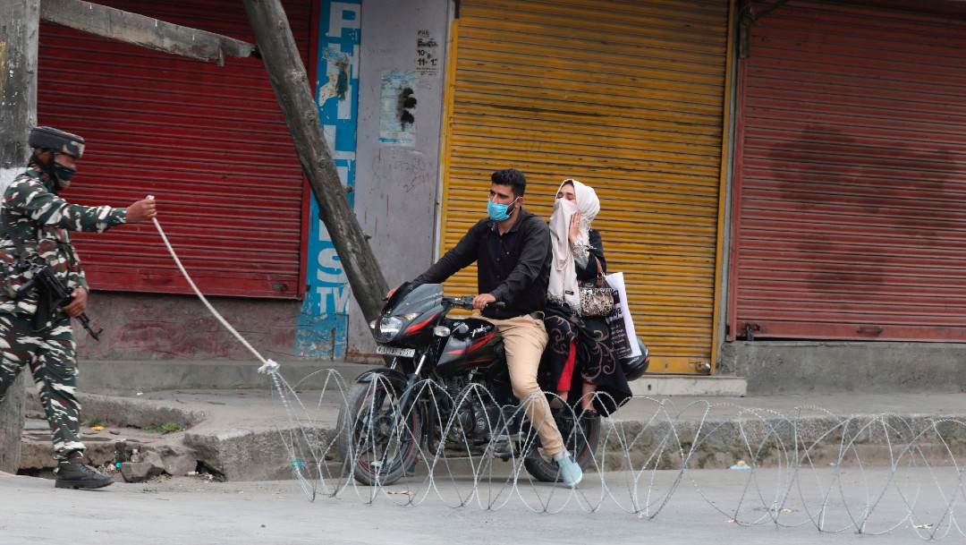 Un soldado abre paso a una pareja en motocicleta en India