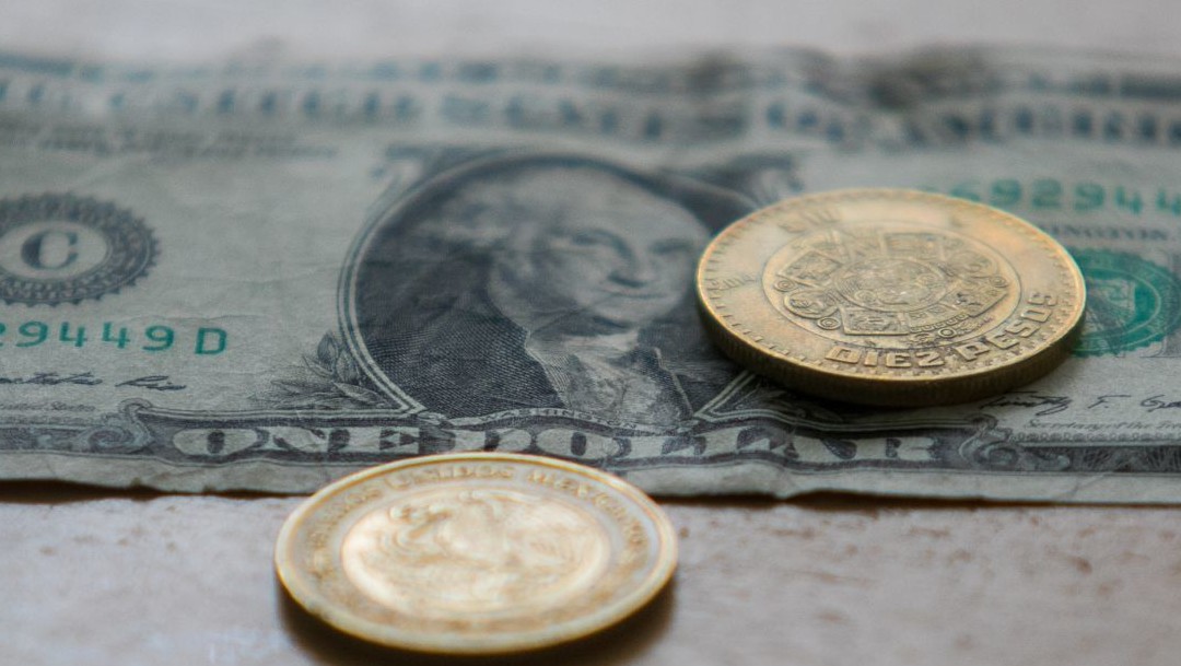 Fotografía que muestra un dólar y dos monedas de 10 pesos mexicanos