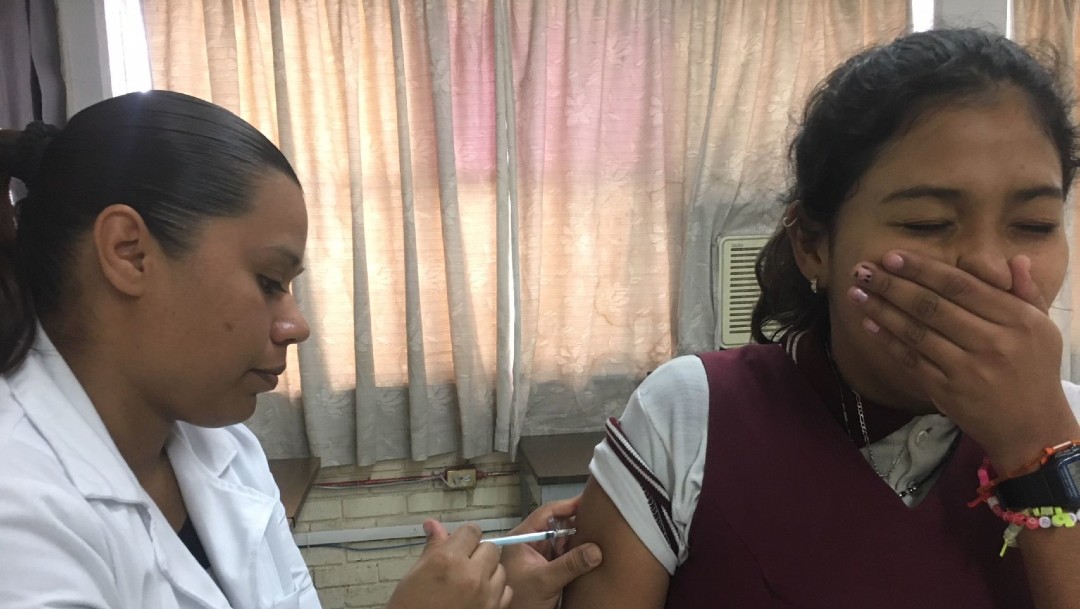 Enfermera vacunando contra influenza a una joven