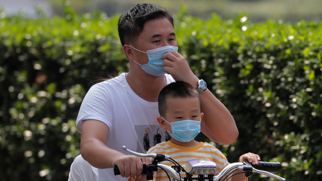 Hombre y niño con cubrebocas en bicicleta en China