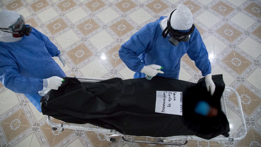 Empleados de una funeraria manipulan un cuerpo tras ser declarado muerto Covid-19. (Foto: Cuartoscuro)