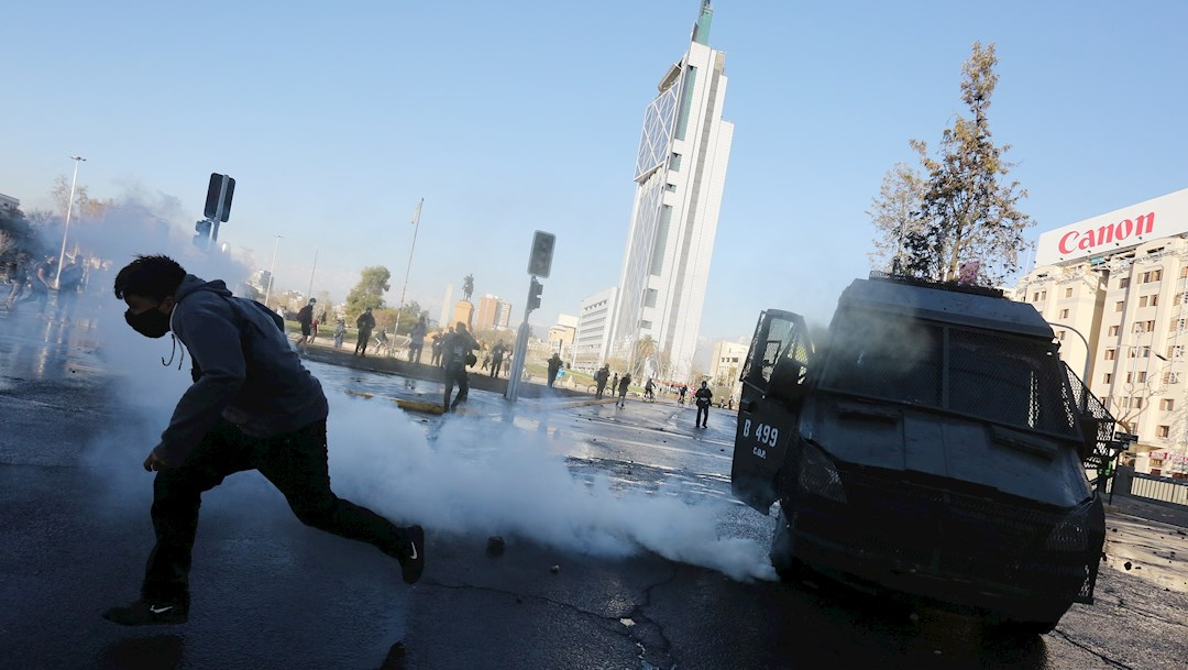 Un hombre corre del gas durante una protesta por la conmemoración del 47ª aniversario del golpe de Estado e inicio de la dictadura en Chile