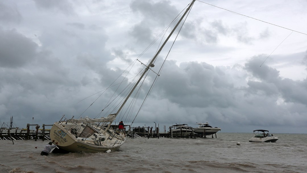 Un hombre empuja una embarcación encallada en una playa por los fuertes vientos de la tormenta tropical Gamma en Cancún