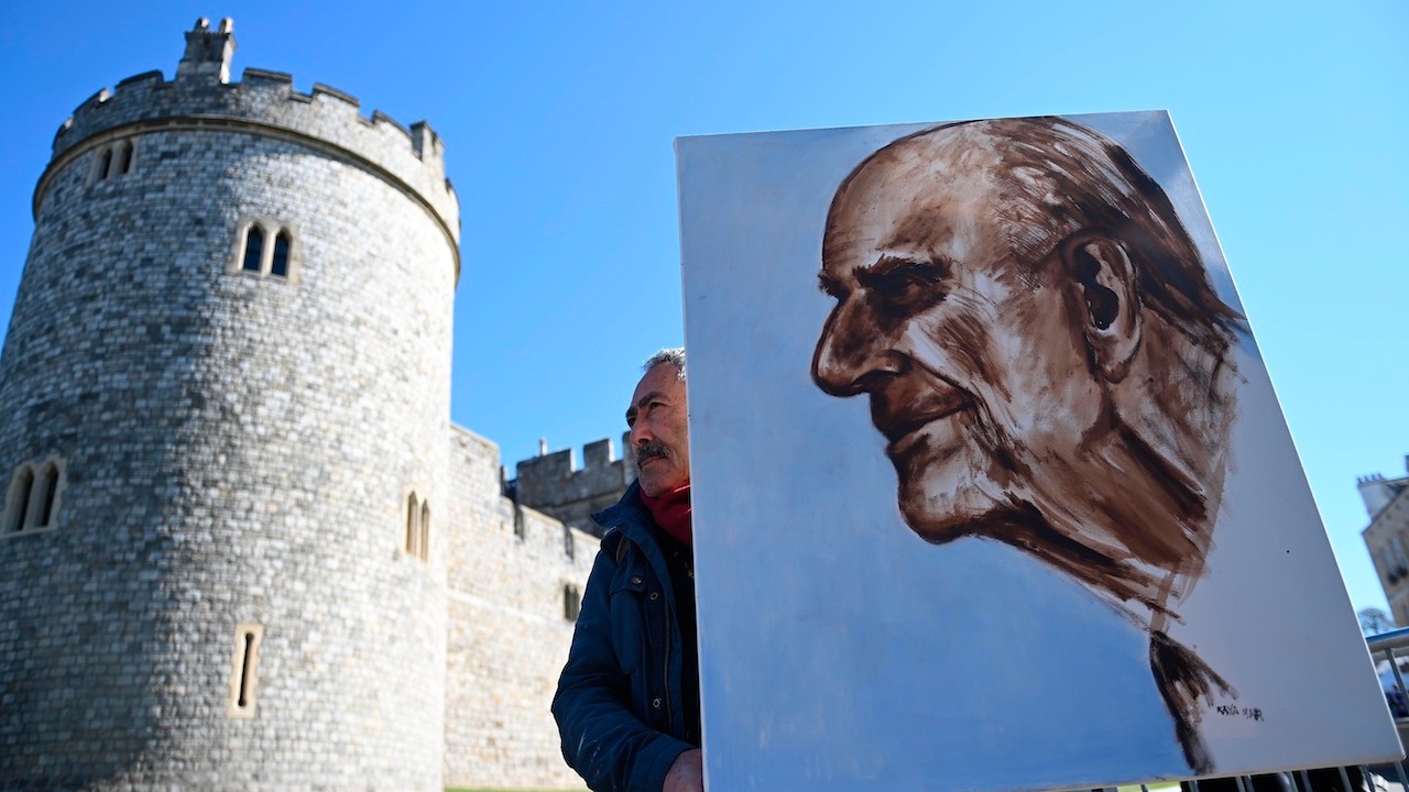 El artista Kaya Marr sostiene un retrato del príncipe Felipe, duque de Edimburgo, frente al castillo de Windsor (EFE)