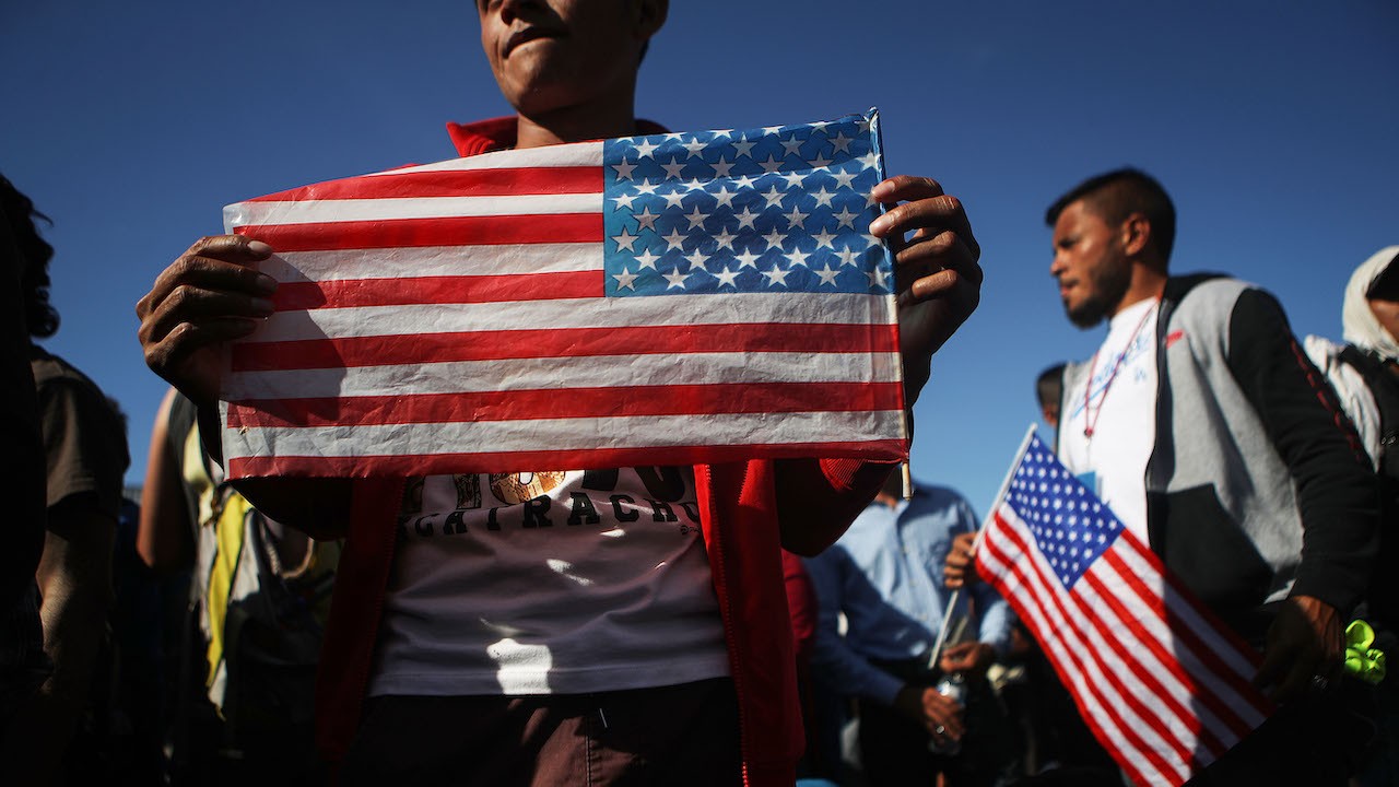Migrantes con banderas de Estados Unidos (Getty Images)