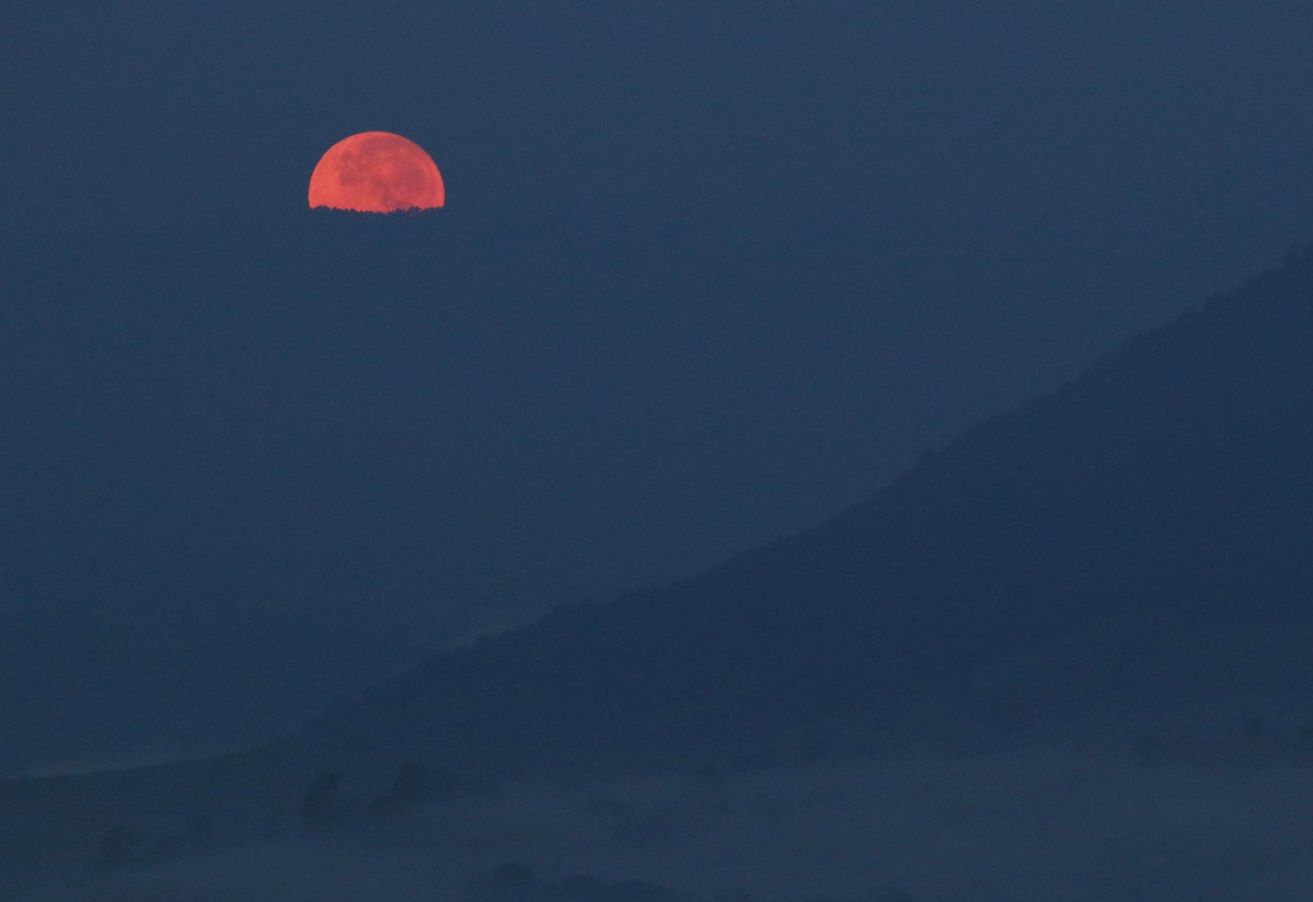 La luna llena adquiere un color naranja en el horizonte durante el amanecer de este día, la imagen tomada en San Pedro Tezontepec.