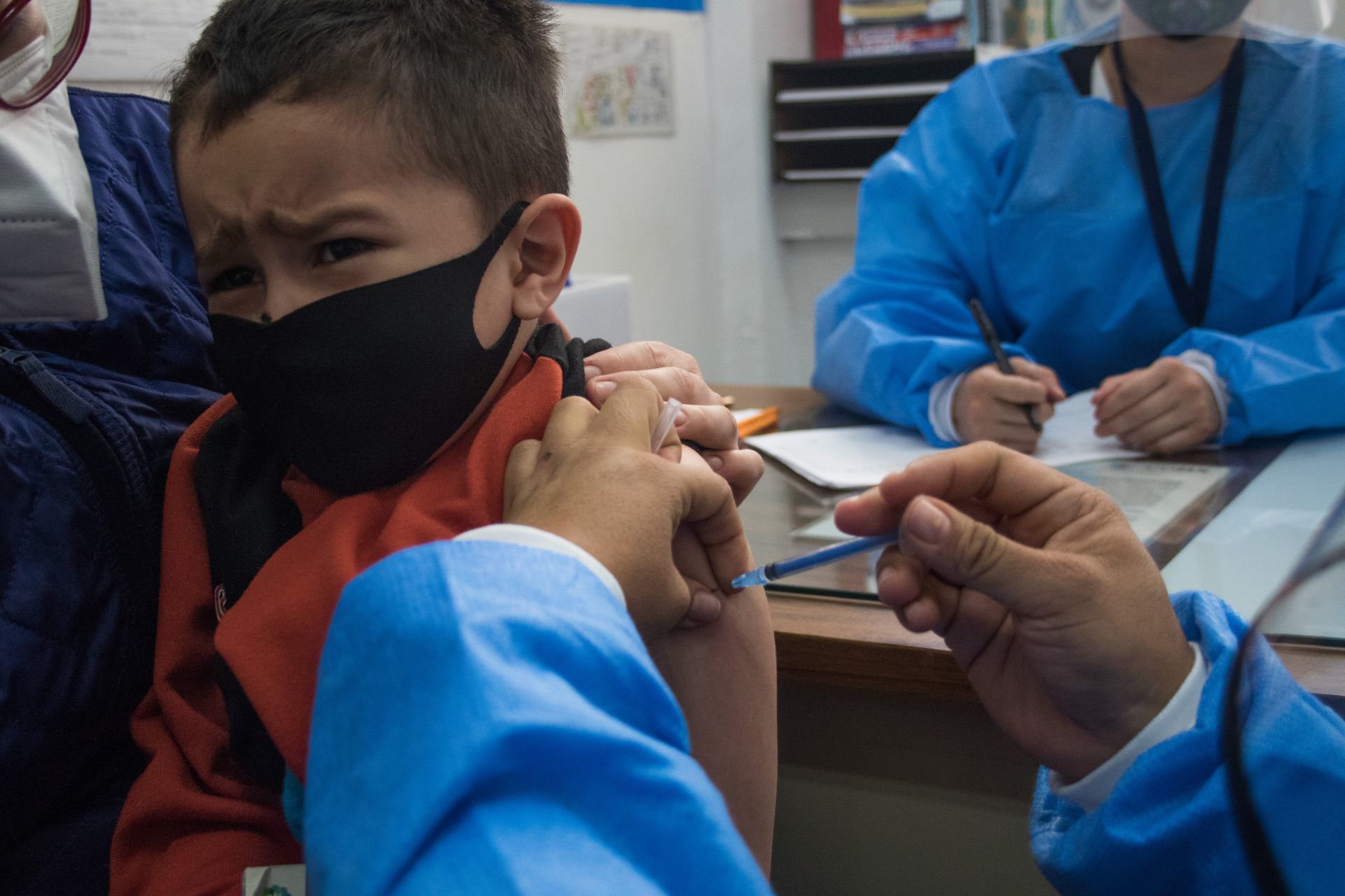 Fotografía que muestra a un niño siendo vacunado por personal de Salud.