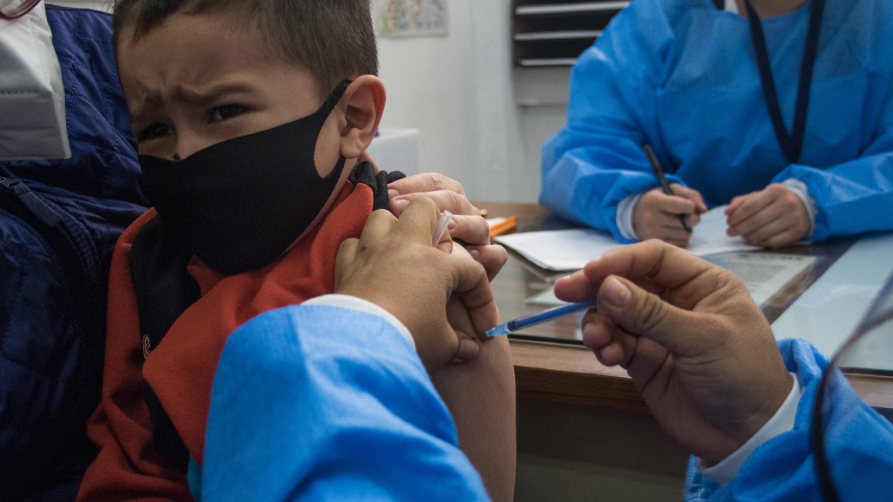 Fotografía que muestra a un niño que es vacunado por una enfermera