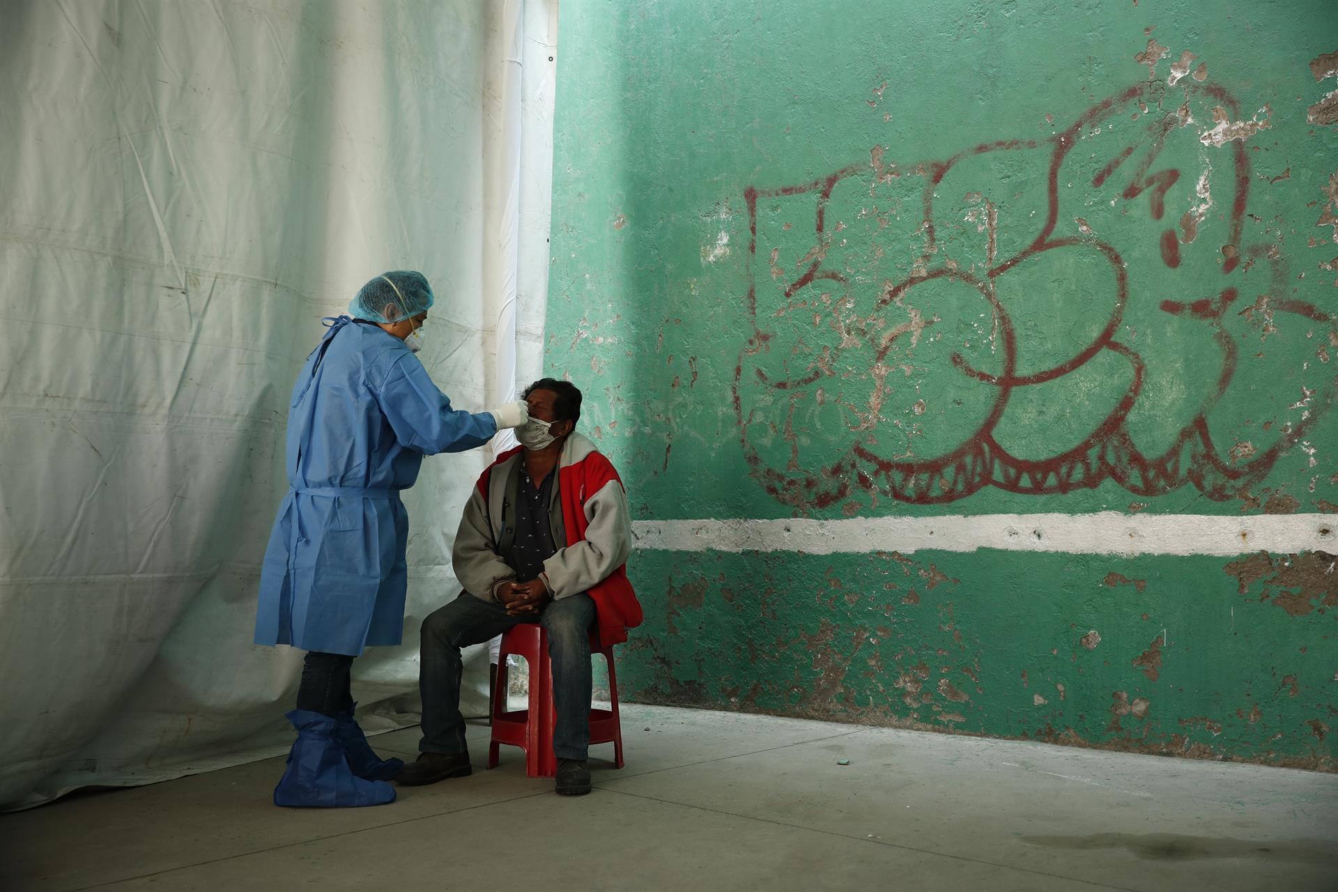 Un trabajador de la salud realiza una prueba rápida para detectar covid a un migrante en CDMX, 13 de diciembre de 2021 (EFE)