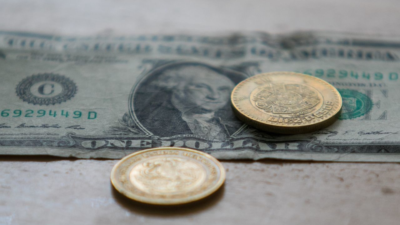 Fotografía que muestra un dólar estadounidense y monedas mexicanas