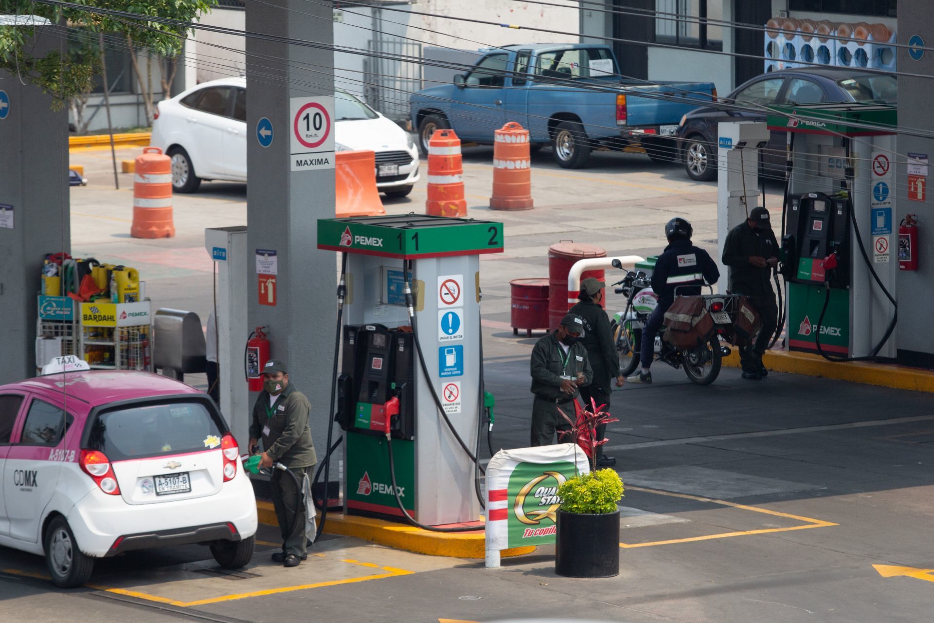 Trabajadores de la gasolinera Pemex suministran de gasolina a autos y motocicletas que solicitan el servicio