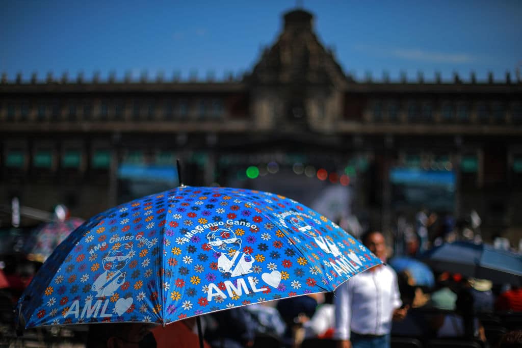 Los asistentes se cubrieron con sombrillas del fuerte sol en la capital mexicana a la espera del mensaje del presidente