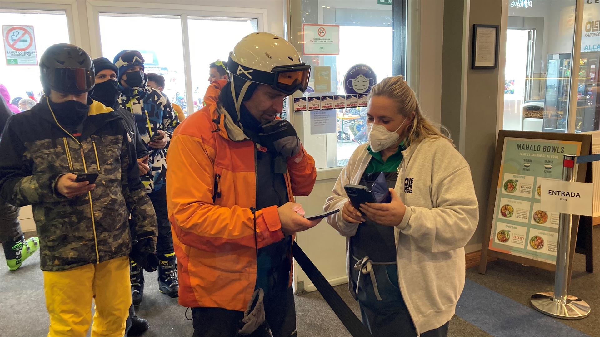 Una trabajadora de la estación de esquí de Sierra Nevada solicita el certificado covid a las personas que entran (EFE)