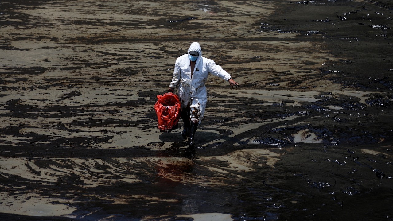 Un trabajador camina tras un derrame de petróleo causado por olas anormales en la playa peruana de Ventanilla, 18 de enero de 2022 (Reuters)
