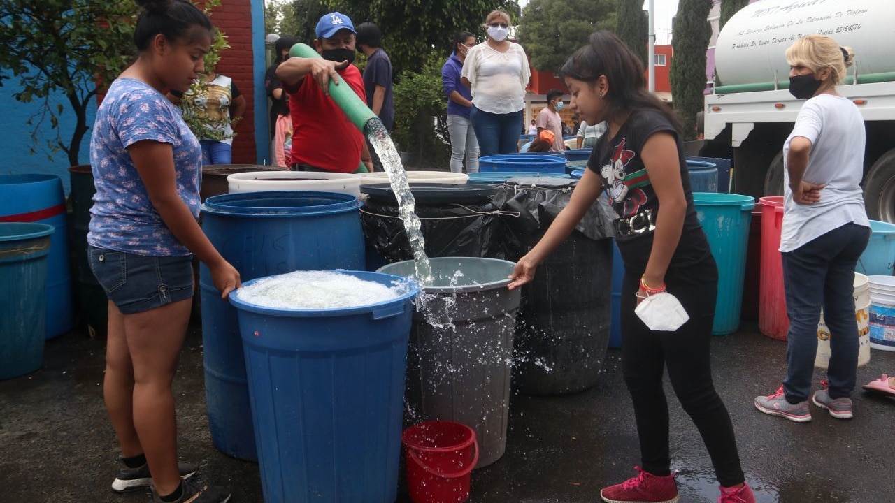 Trabajadores de pipas de agua llenan botes con el vital líquido a vecinos de la alcaldía Iztapalapa, en Ciudad de México