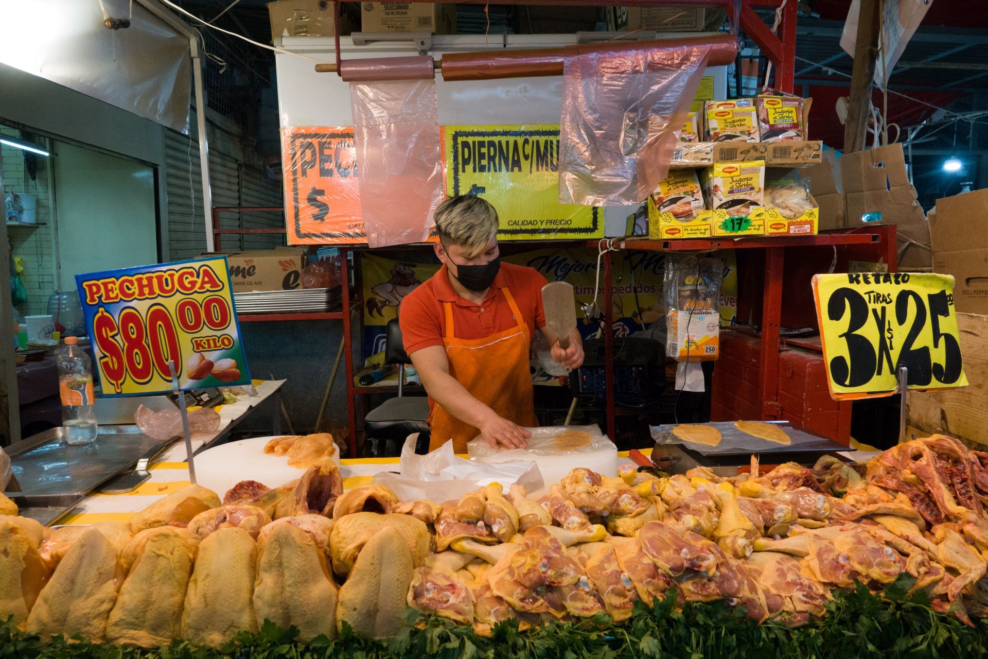 Un joven aplasta pechugas de pollo en el Mercado la Merced