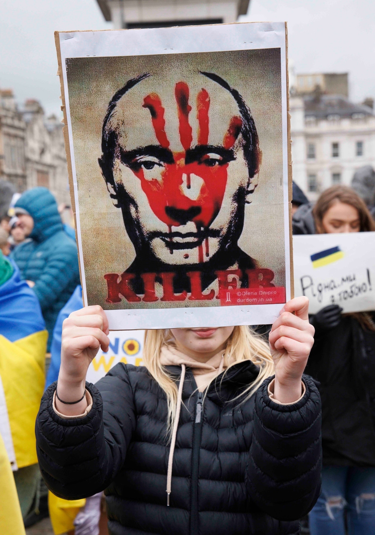Una manifestante en Gran Bretaña sostiene una pancarta para protestar contra la invasión de Rusia a Ucrania