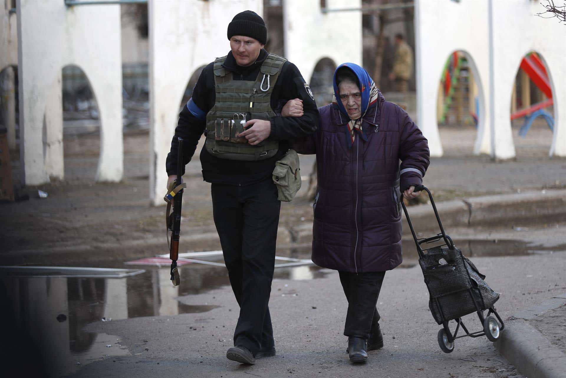 Un policía ucraniano ayuda a evacuar a una mujer de un edificio alcanzado por misiles rusos (EFE)